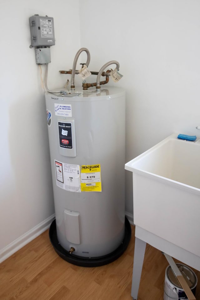 utility room with water heater and a sink