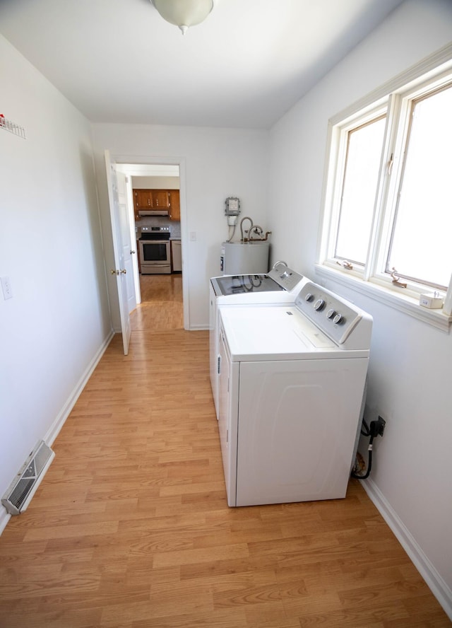 laundry area featuring washing machine and dryer, laundry area, visible vents, light wood-style floors, and water heater