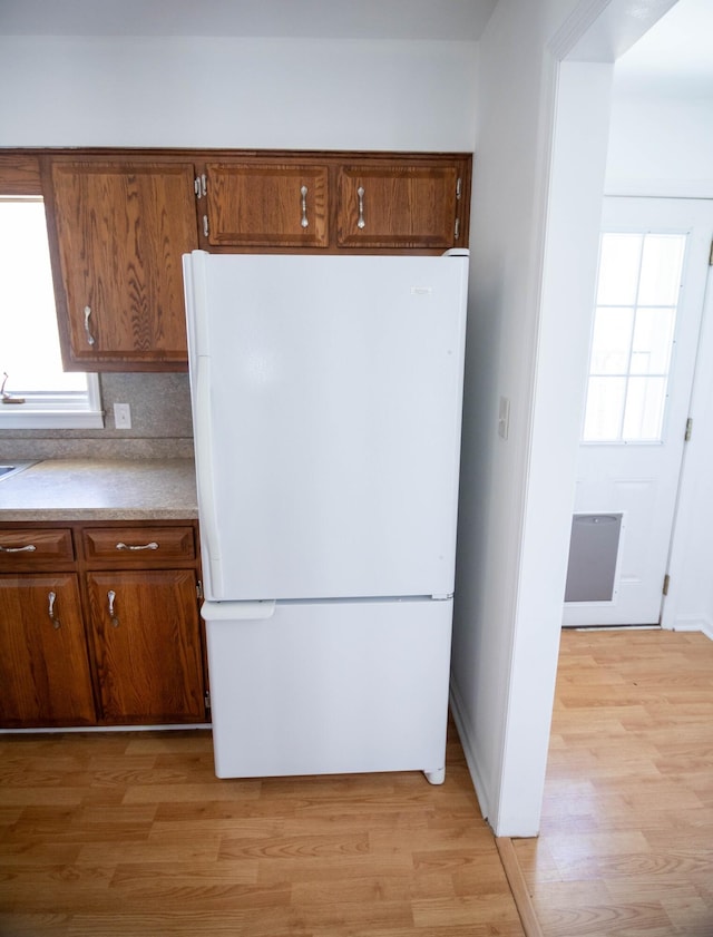 kitchen with light wood-type flooring, freestanding refrigerator, and a healthy amount of sunlight