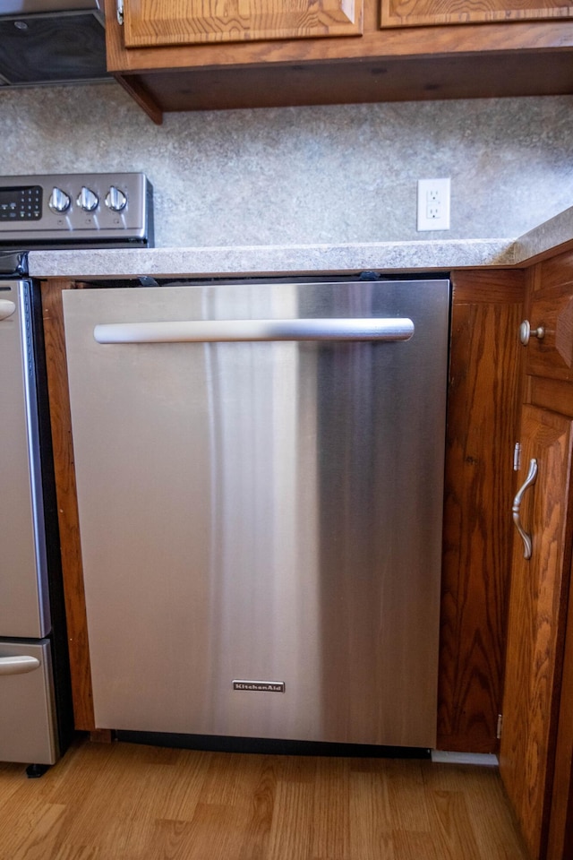 interior details with brown cabinetry, light countertops, dishwasher, and light wood finished floors