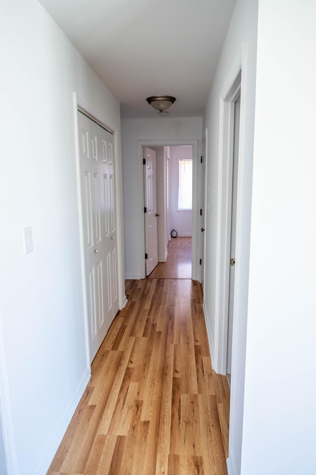 corridor featuring light wood-type flooring and baseboards