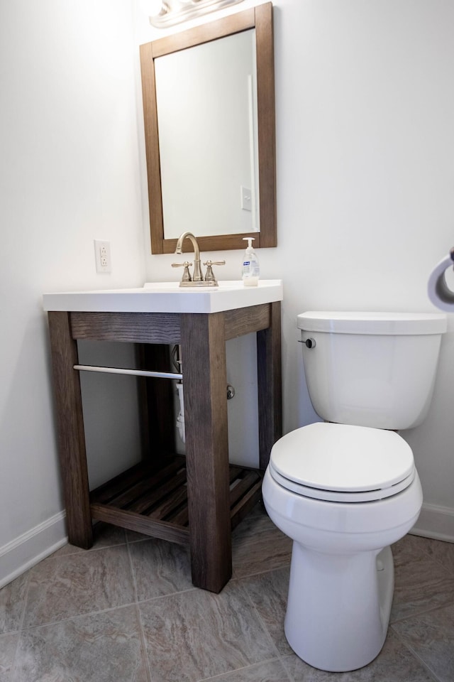 half bathroom with a sink, toilet, and baseboards