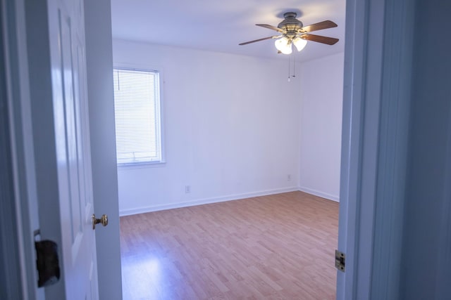 empty room with ceiling fan, baseboards, and wood finished floors