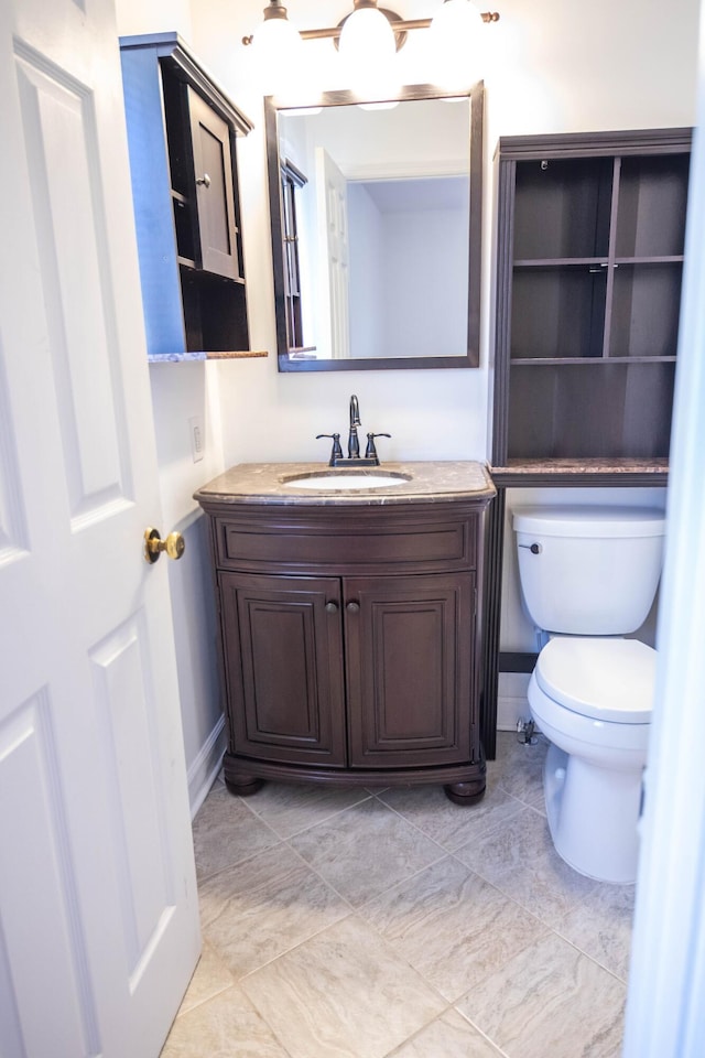 bathroom featuring vanity, toilet, and baseboards