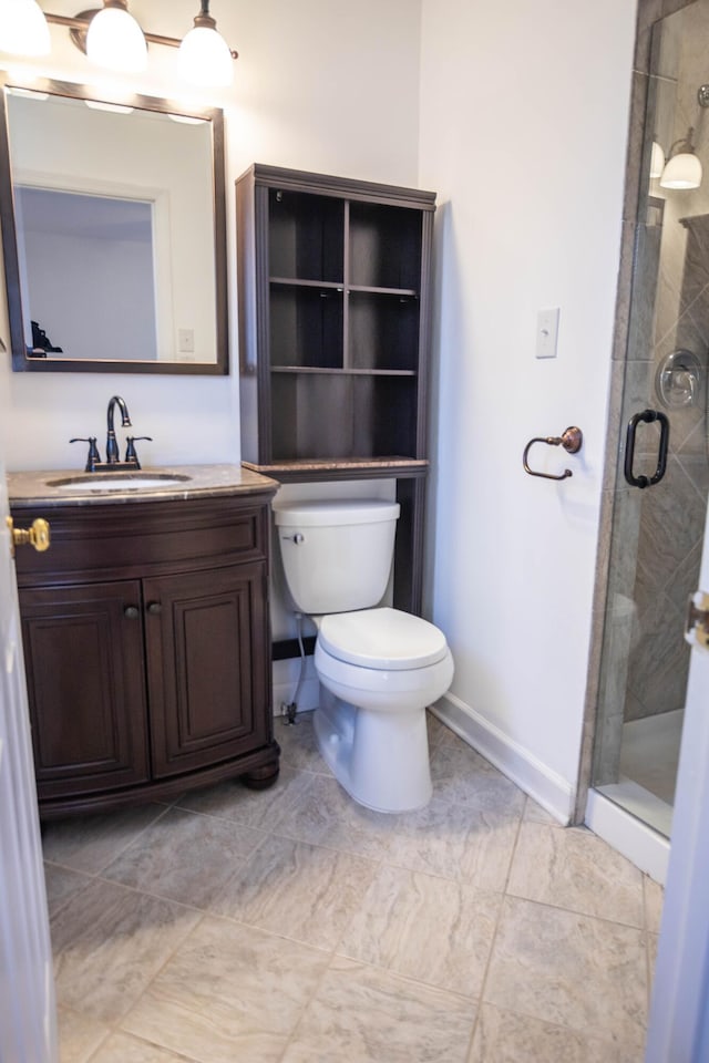 full bathroom with toilet, a stall shower, baseboards, and vanity