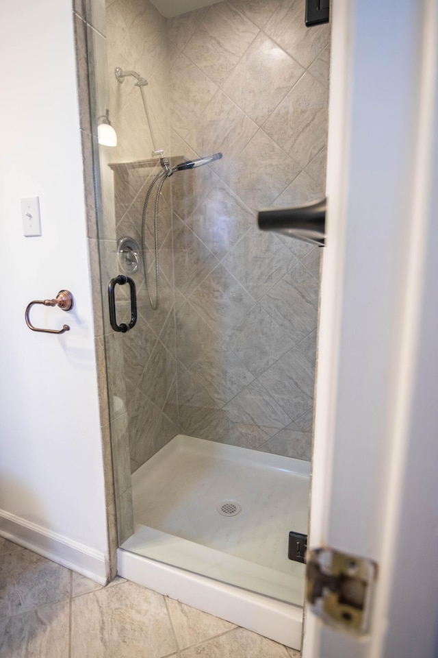 full bathroom featuring a shower stall and baseboards