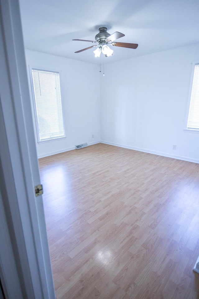 spare room featuring a wealth of natural light, visible vents, and wood finished floors