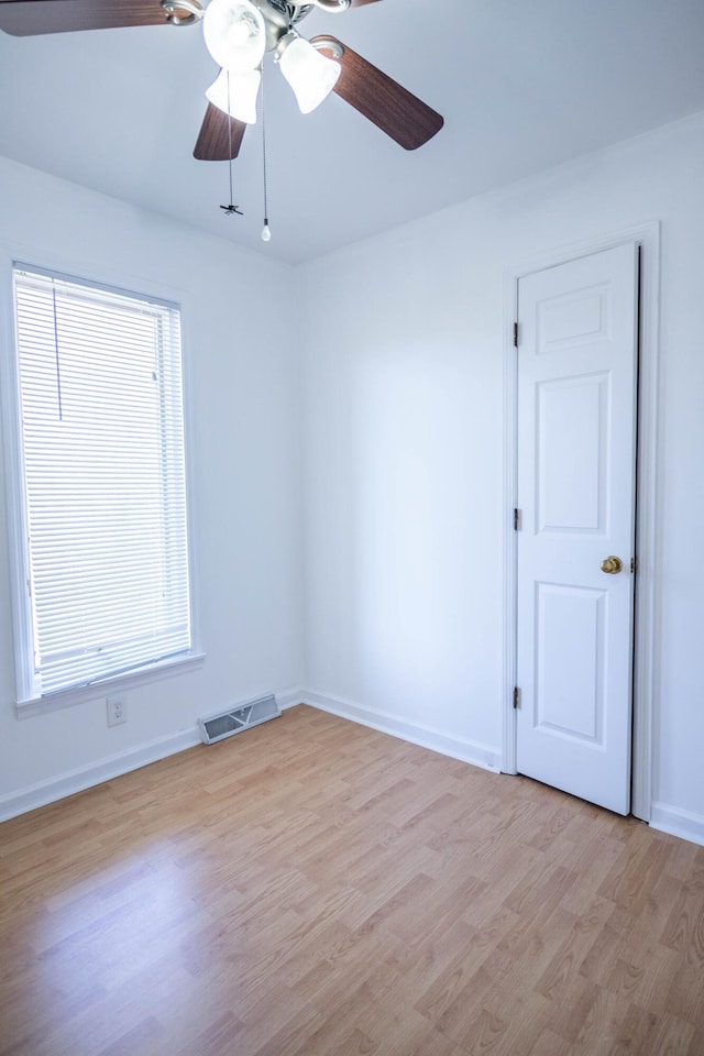 spare room featuring light wood-style floors, visible vents, baseboards, and a ceiling fan