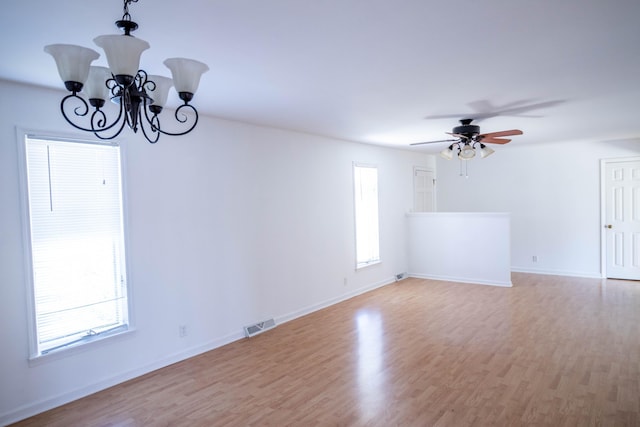 spare room with ceiling fan with notable chandelier, light wood-type flooring, visible vents, and baseboards