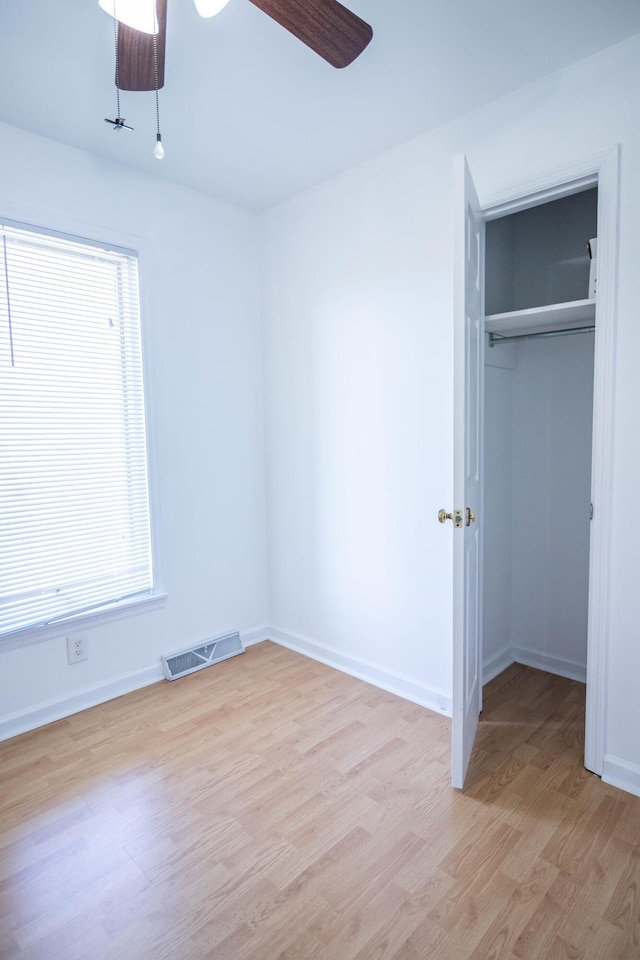 unfurnished bedroom featuring light wood finished floors, baseboards, visible vents, a walk in closet, and a closet