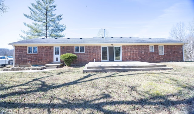 rear view of property with brick siding, a yard, and a patio