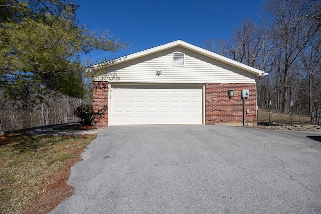 view of property exterior featuring a garage, brick siding, and aphalt driveway