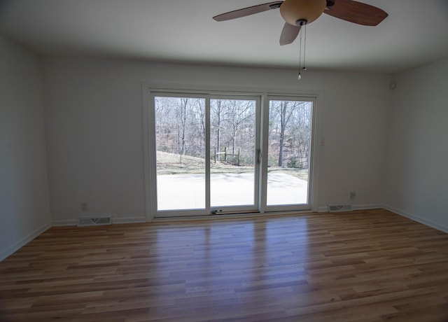 unfurnished room featuring baseboards, visible vents, and wood finished floors