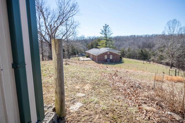 view of yard featuring a forest view and fence