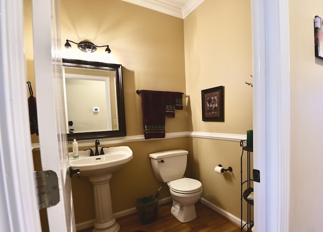 half bathroom featuring baseboards, wood finished floors, toilet, and crown molding