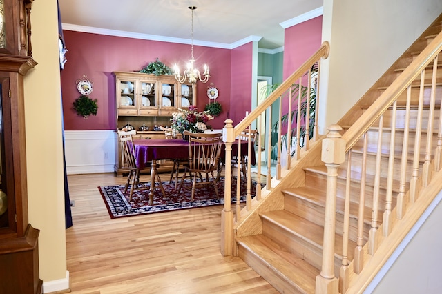 dining room featuring a chandelier, stairway, wood finished floors, and crown molding