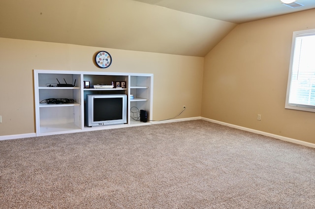 interior space featuring built in features, baseboards, vaulted ceiling, and carpet flooring