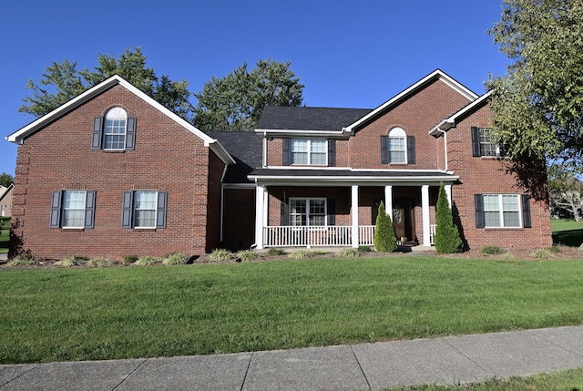 view of front facade with covered porch, brick siding, and a front lawn