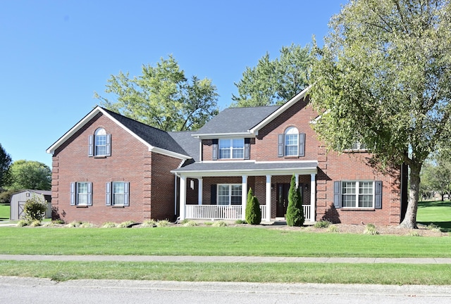 view of front facade featuring brick siding, a porch, and a front yard