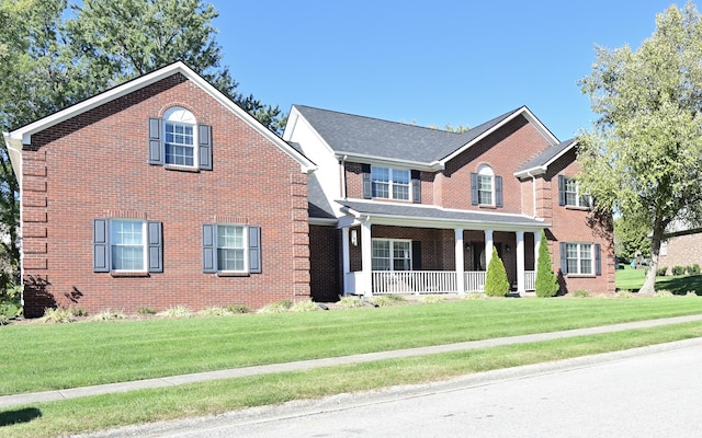 view of front of home with a front yard, covered porch, and brick siding