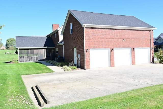 view of home's exterior featuring a sunroom, brick siding, a yard, and driveway