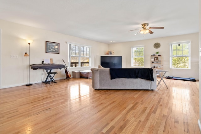 living area featuring baseboards, a ceiling fan, and light wood-style floors