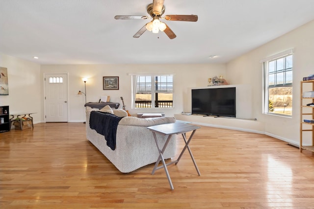 living area featuring baseboards, a ceiling fan, and light wood-style floors