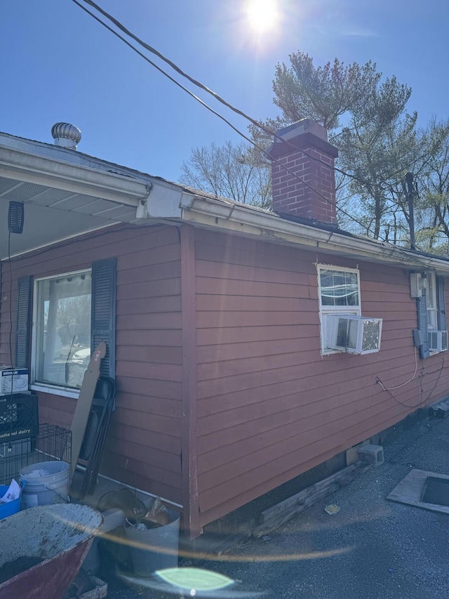 view of side of property with cooling unit and a chimney