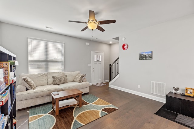 living room featuring a ceiling fan, stairway, dark wood-style floors, and visible vents