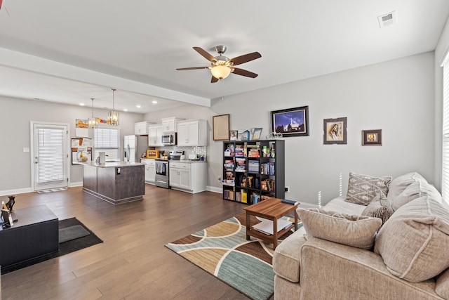 living area featuring dark wood-style floors, visible vents, baseboards, and a ceiling fan