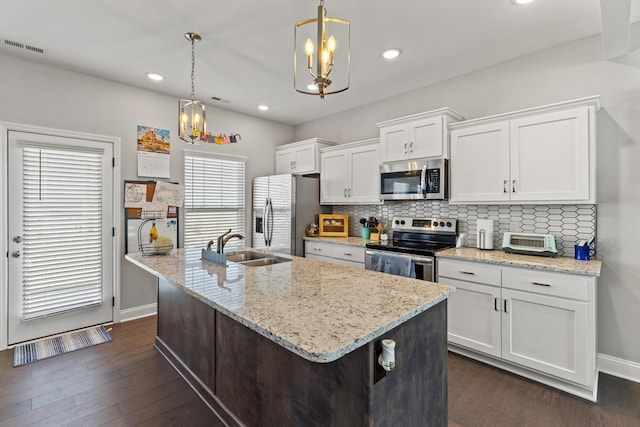 kitchen with a chandelier, decorative backsplash, stainless steel appliances, white cabinetry, and a sink