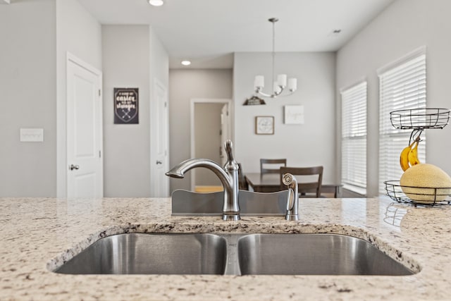 kitchen featuring a sink, decorative light fixtures, light stone counters, and recessed lighting