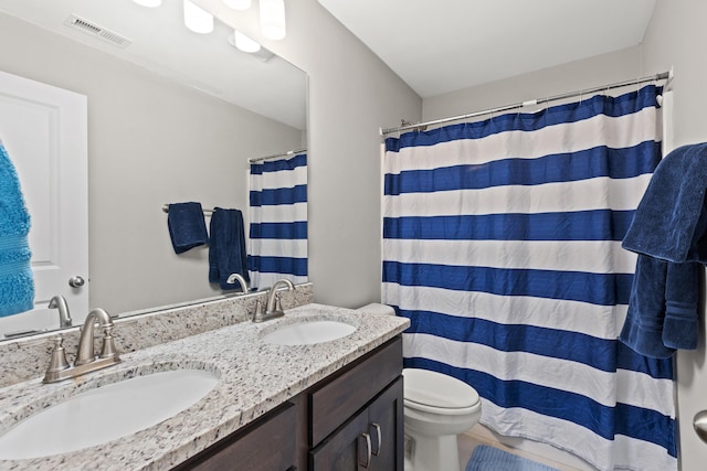 bathroom featuring double vanity, toilet, visible vents, and a sink