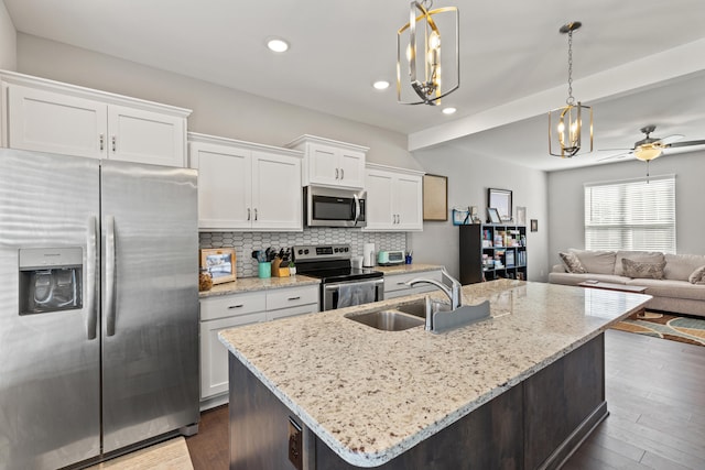 kitchen with dark wood-style flooring, a sink, stainless steel appliances, white cabinetry, and backsplash