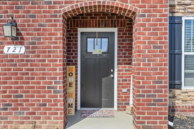 view of exterior entry featuring brick siding