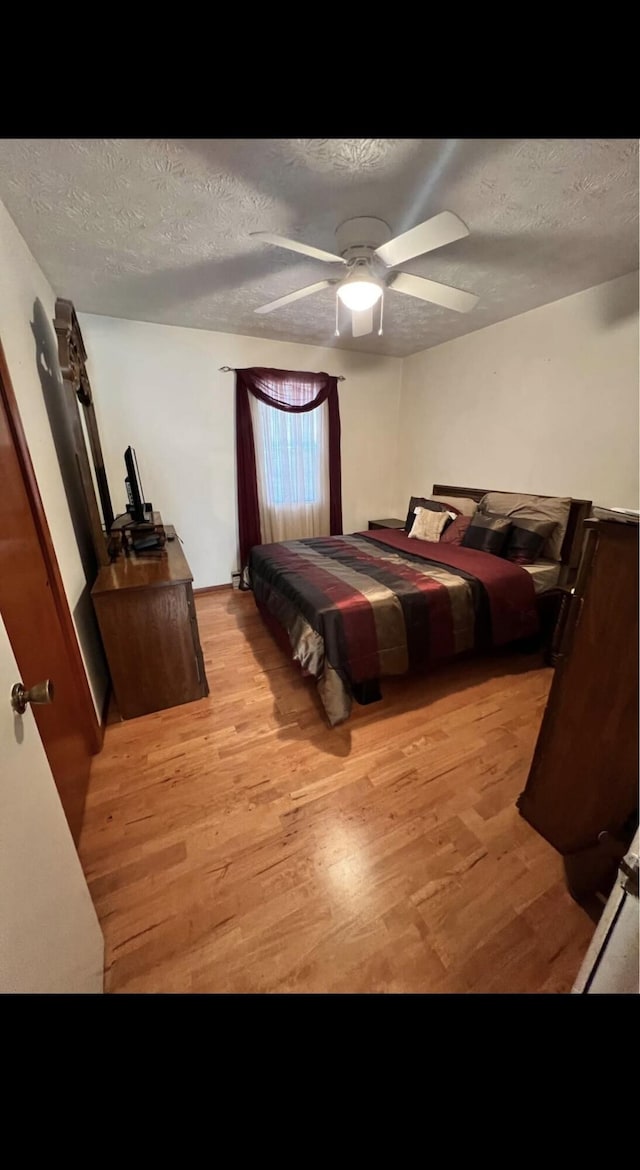 bedroom featuring light wood-style floors, a ceiling fan, and a textured ceiling