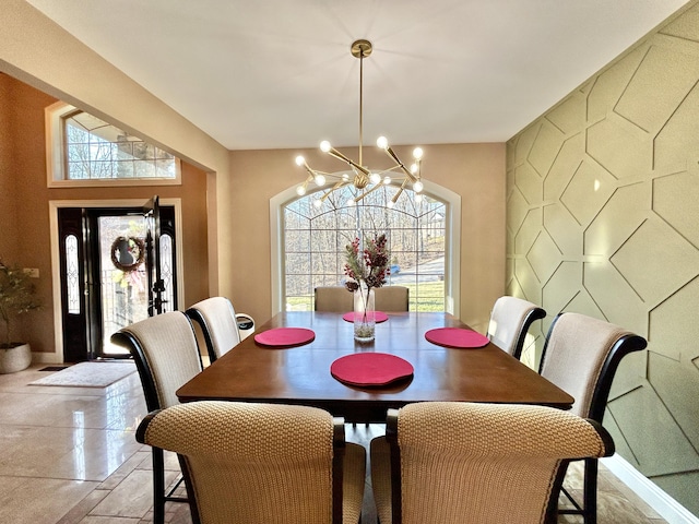 dining room featuring baseboards, an accent wall, and a chandelier