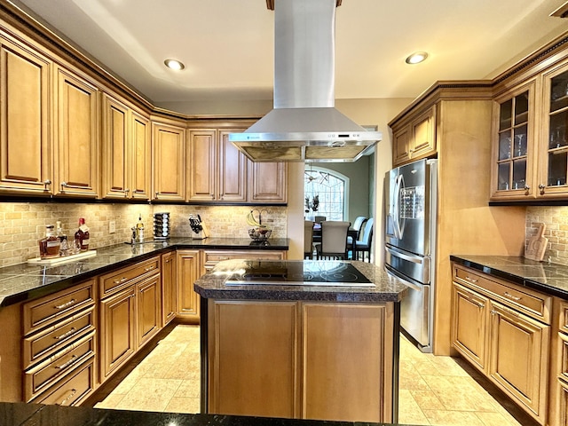 kitchen with island exhaust hood, black electric cooktop, a center island, dark countertops, and stainless steel fridge