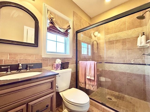 bathroom with toilet, a stall shower, tile walls, and vanity