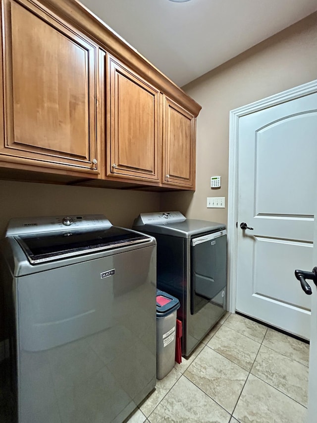 laundry room featuring separate washer and dryer, light tile patterned flooring, and cabinet space