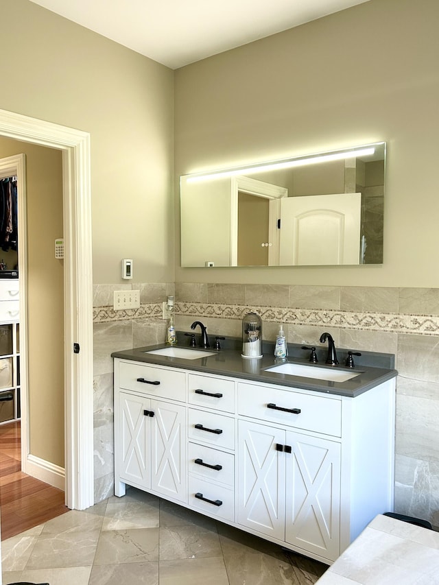 bathroom featuring double vanity, marble finish floor, tile walls, and a sink