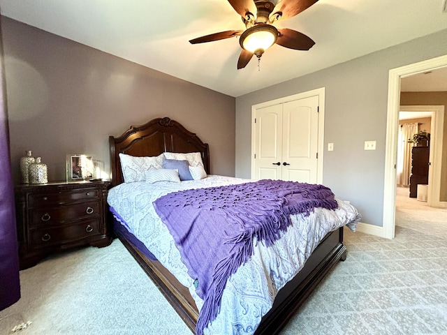 bedroom featuring a ceiling fan, baseboards, a closet, and light colored carpet