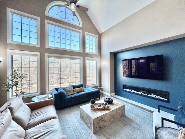 living room featuring high vaulted ceiling, wood finished floors, a ceiling fan, and baseboards