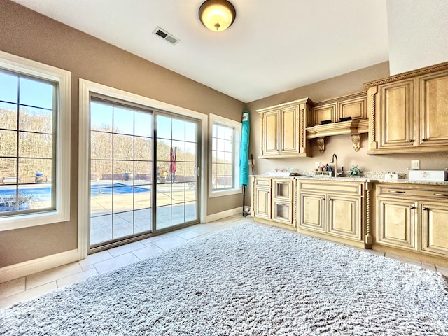 interior space featuring baseboards, visible vents, a sink, and light tile patterned flooring