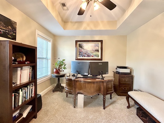 office area with visible vents, baseboards, ceiling fan, a tray ceiling, and carpet floors