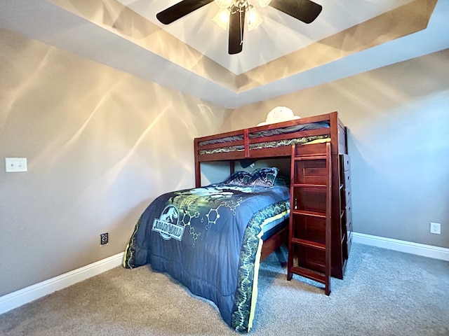 carpeted bedroom featuring baseboards, a tray ceiling, and ceiling fan