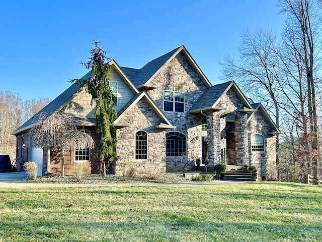 view of front of property with an attached garage, stone siding, and a front yard