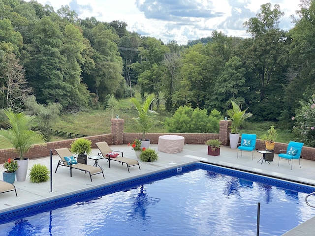 outdoor pool with a patio and a forest view