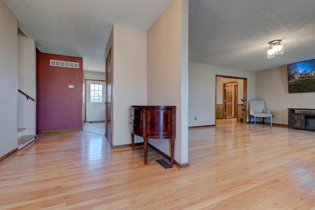 interior space with light wood-type flooring, visible vents, baseboards, and stairs