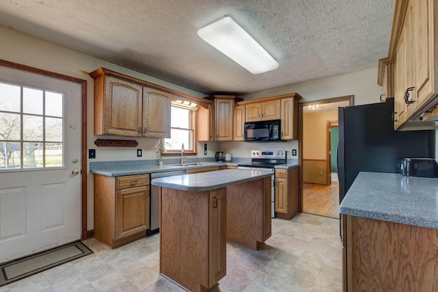 kitchen with stainless steel appliances, a sink, a center island, light floors, and brown cabinetry